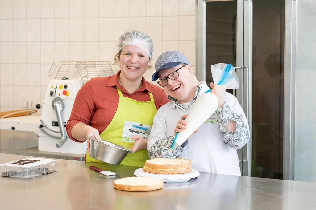 Medewerker en cliënt maken taart in Bakkerij De Likkepot